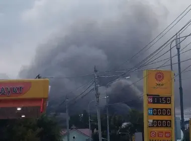 Thick gray smoke rises behind buildings, power lines, and a fuel station in Samara after a reported missile strike.