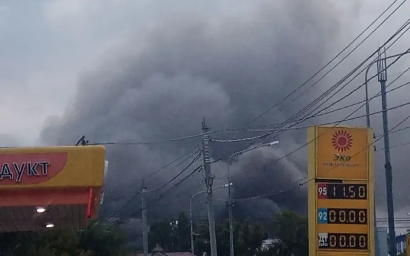 Thick gray smoke rises behind buildings, power lines, and a fuel station in Samara after a reported missile strike.