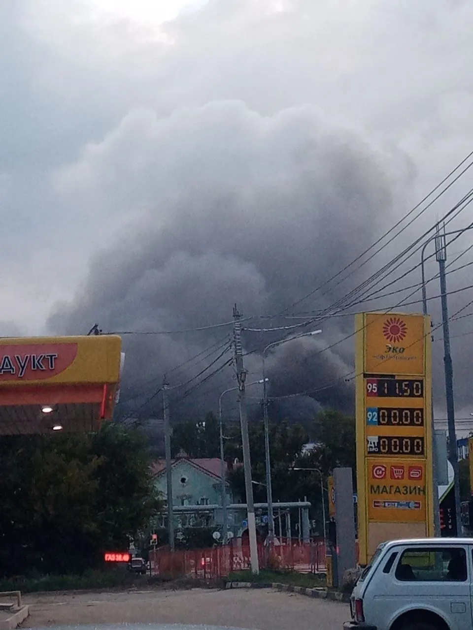 Thick gray smoke rises behind buildings, power lines, and a fuel station in Samara after a reported missile strike.