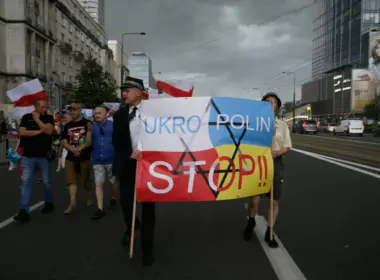 Demonstrators carrying Polish flags march behind a banner in Polish and Ukrainian colors reading “UKRO POLIN STOP!!” with a crossed-out Star of David.