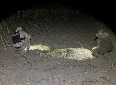 Two investigators examine a blast site with flashlights in a cornfield near Talmaza, Moldova, at night.
