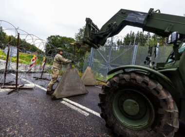 Lithuanian soldier installs concrete barriers and razor wire across a road during a civil defense exercise.