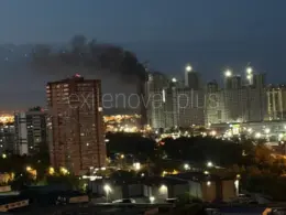 Smoke rises behind illuminated apartment buildings in Moscow at night following a reported Ukrainian drone attack.