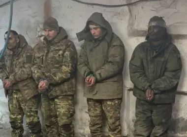Four captured fighters who fought for Russia stand against a wall with their hands bound.