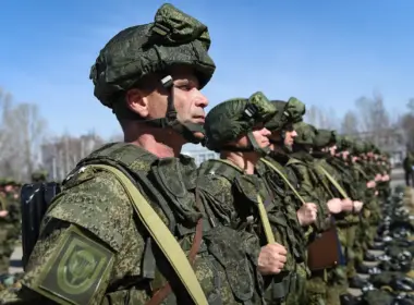 Russian soldiers in camouflage uniforms and helmets stand in formation outdoors.