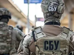 SBU officers in camouflage and tactical gear, seen from behind during an operation.