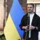 Ruslan Kravchenko speaks beside a large Ukrainian flag at a housing-rehabilitation event in Irpin in June 2023.