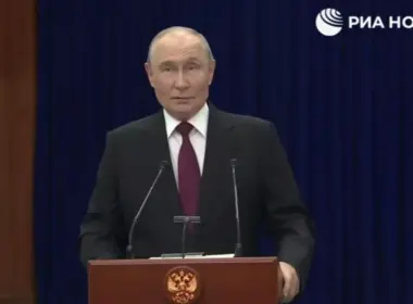 Vladimir Putin stands behind a lectern during a press conference, with the RIA Novosti logo visible above him.
