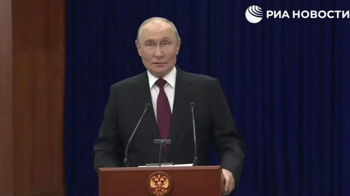 Vladimir Putin stands behind a lectern during a press conference, with the RIA Novosti logo visible above him.