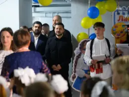 President Volodymyr Zelenskyy watches as a pupil in an embroidered shirt speaks at a school event decorated with Ukrainian-colored balloons.