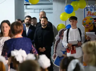 President Volodymyr Zelenskyy watches as a pupil in an embroidered shirt speaks at a school event decorated with Ukrainian-colored balloons.