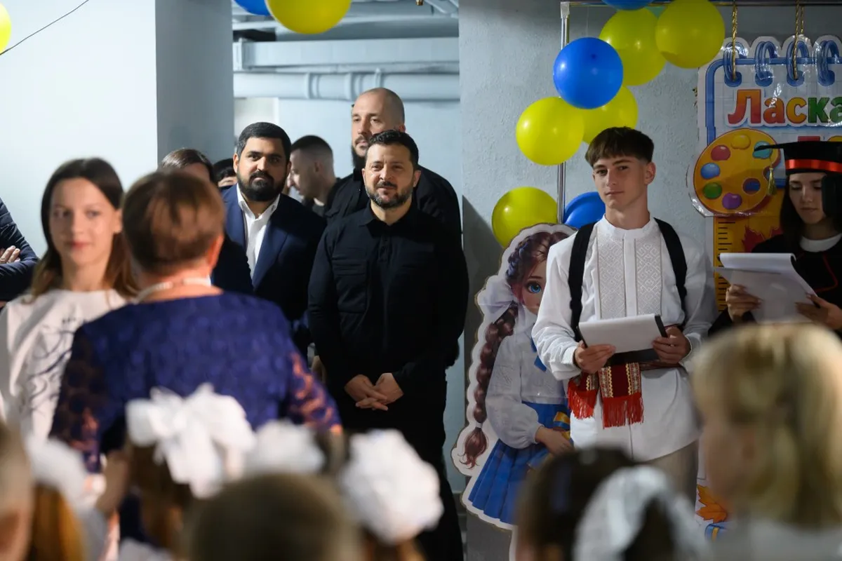 President Volodymyr Zelenskyy watches as a pupil in an embroidered shirt speaks at a school event decorated with Ukrainian-colored balloons.
