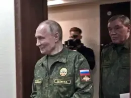 Vladimir Putin walks through a doorway in a military uniform, followed by Russian Chief of the General Staff Valery Gerasimov.
