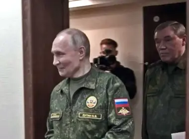 Vladimir Putin walks through a doorway in a military uniform, followed by Russian Chief of the General Staff Valery Gerasimov.