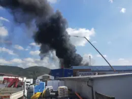 Thick black smoke billows from the roof of the ZVS Holding ammunition plant in Snina beside an extended crane.