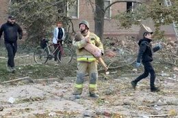 Rescue worker carries a child from the rubble following a Russian missile strike on an apartment building in Pryluky, Chernihiv Oblast.