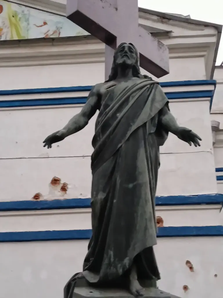russian glide bombs scarred statue christ damaged 19th-century church sumy · post grave dmytro sukhanov front saints peter paul ukraine shrapnel marks wall behind after strike 29 2026 foto спасо-преображенський
